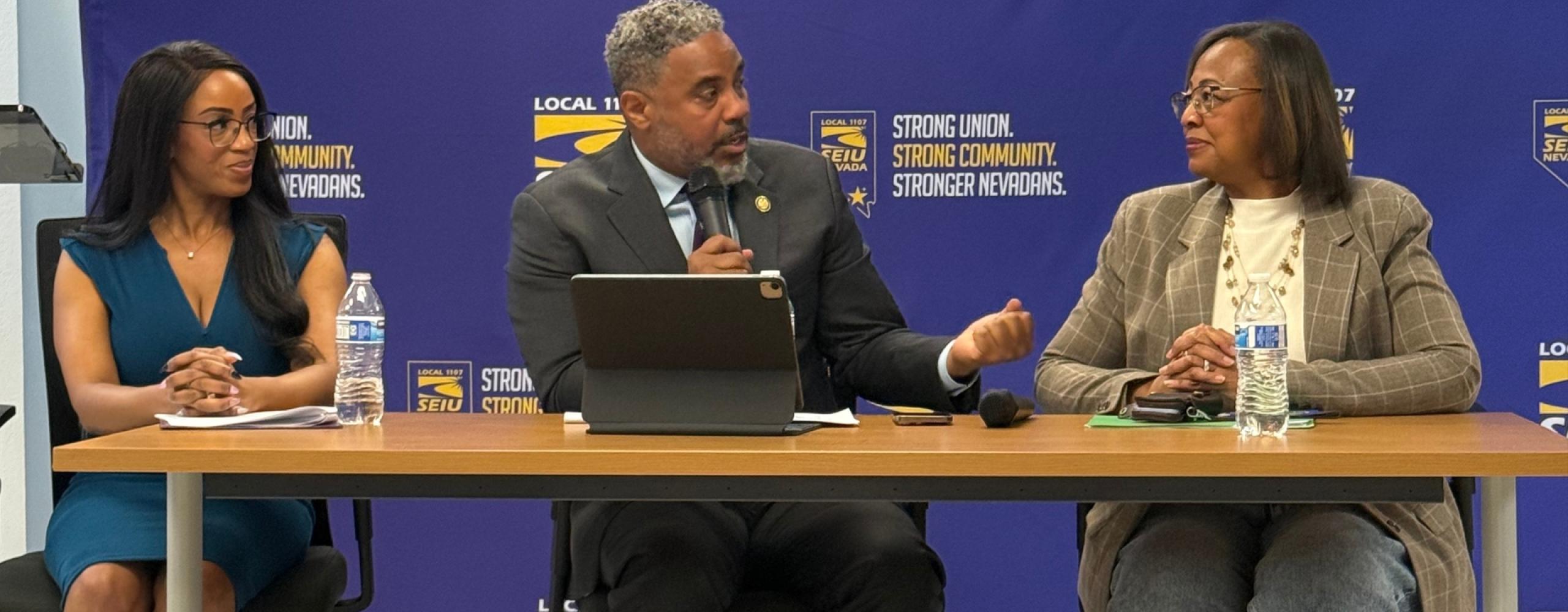 Congressman Steven Horsford speaks into a microphone while seated at a table between two women during a panel event at SEIU Nevada. The backdrop features SEIU branding and the slogan "Strong Union. Strong Community. Stronger Nevadans." All three individuals appear engaged in discussion, with water bottles and notes on the table in front of them.