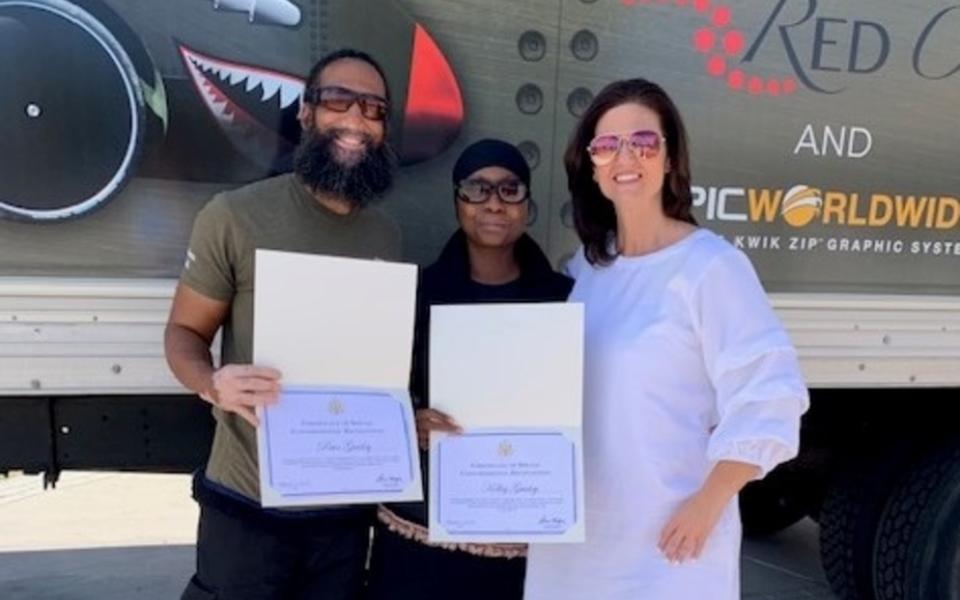 Samantha Bivins from Congressman Steven Horsford's office presents certificates to Paul and Kelley Guidry